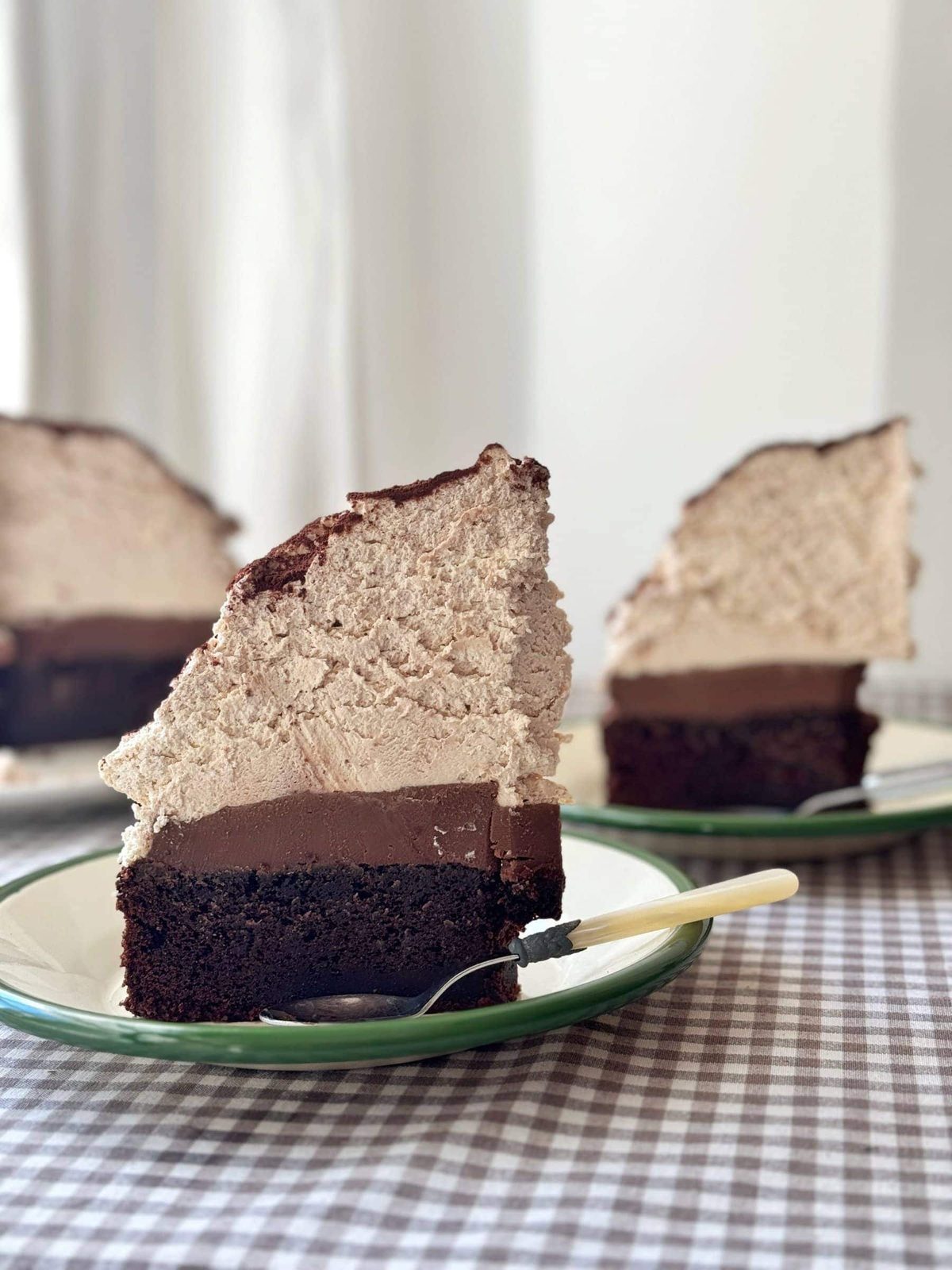 slice of chocolate mud cake with malted whipped cream stood on a green plate