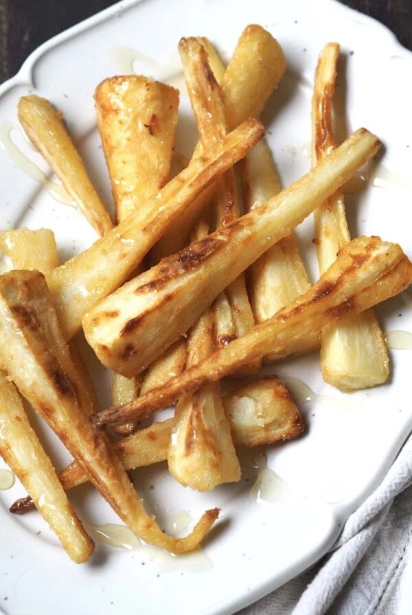 Honey glazed parsnips close up on a white serving platter.