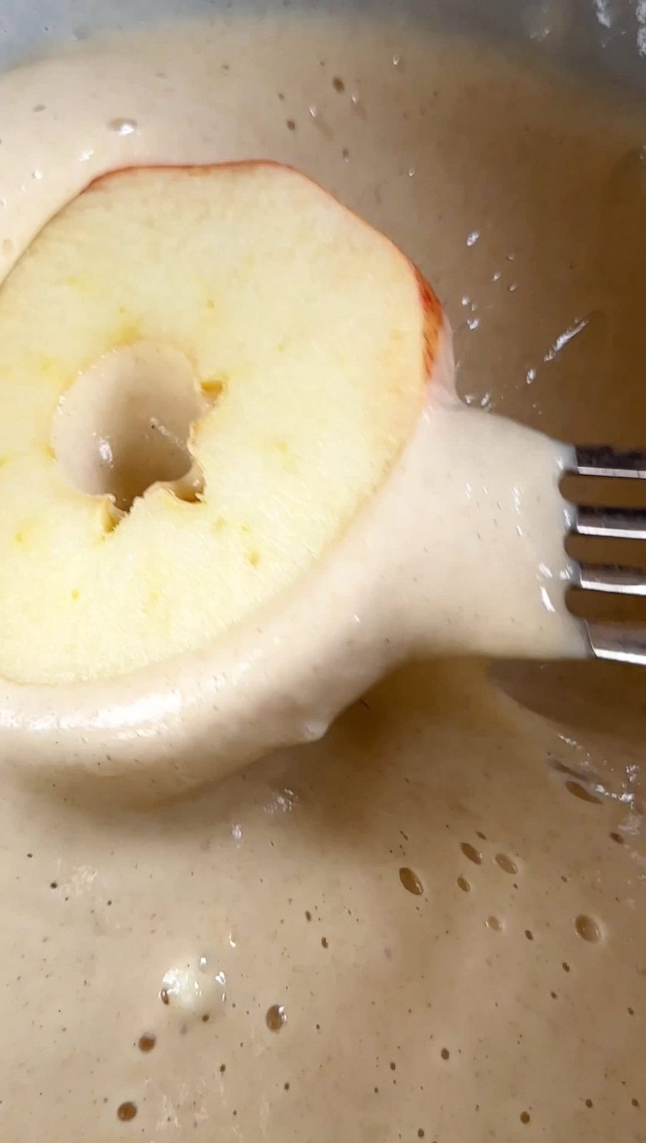 Dipping apple slice into beignet batter.