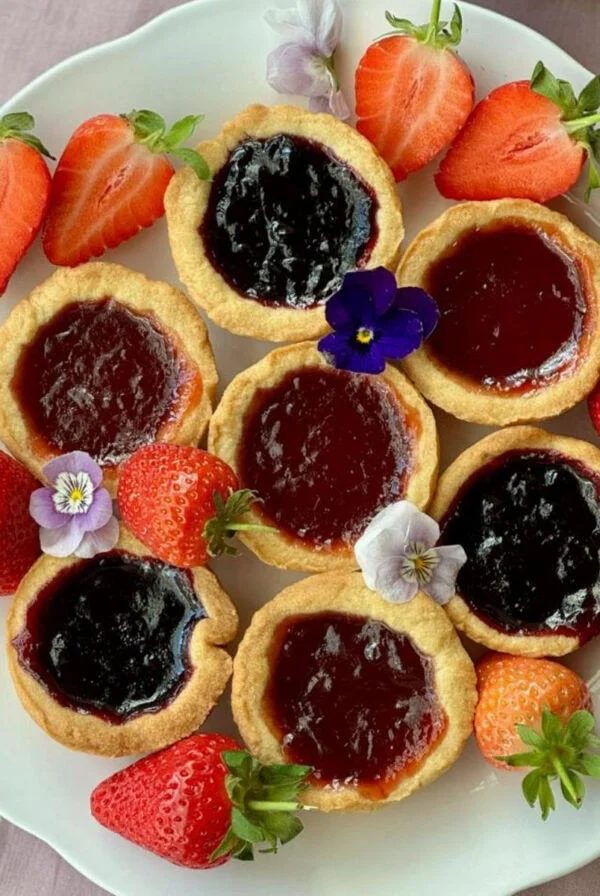 jam tartlets on a plate with edible flowers.