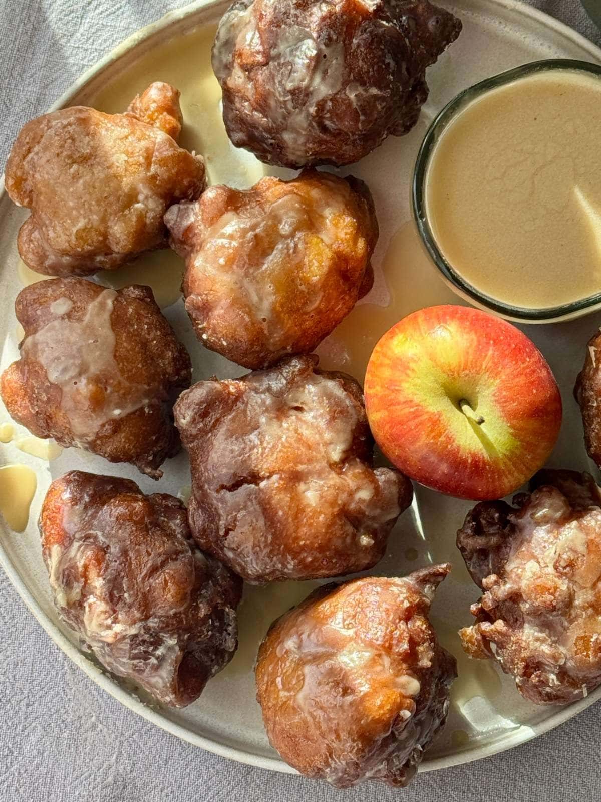 Applesauce fritters on a plate with an apple.