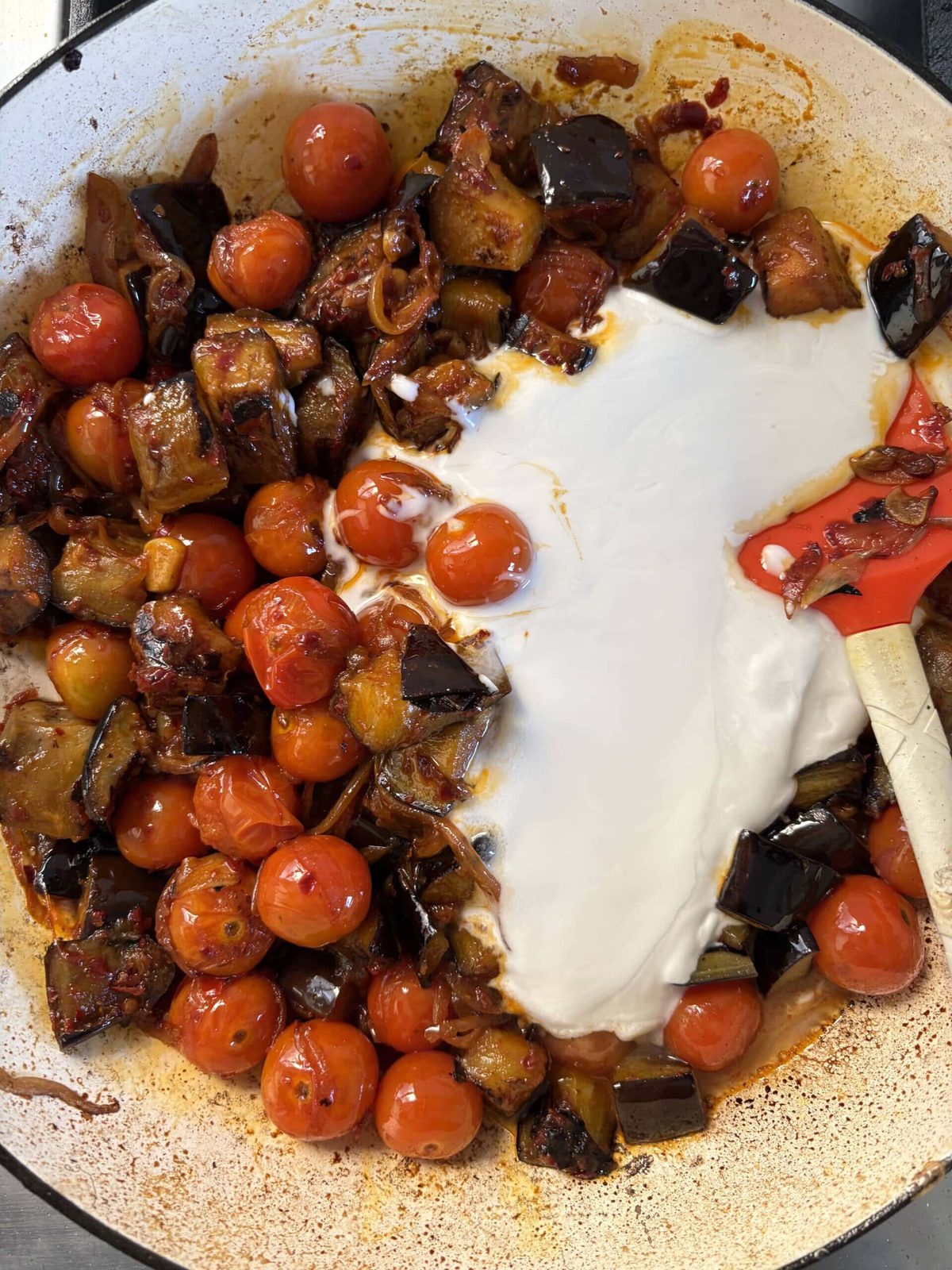 adding coconut milk to the aubergine curry.