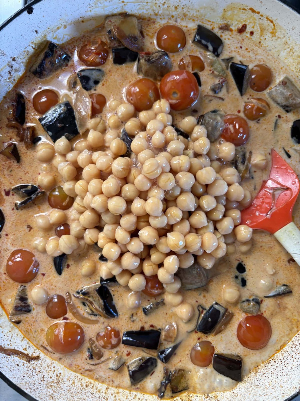 adding chickpeas to the aubergine curry.