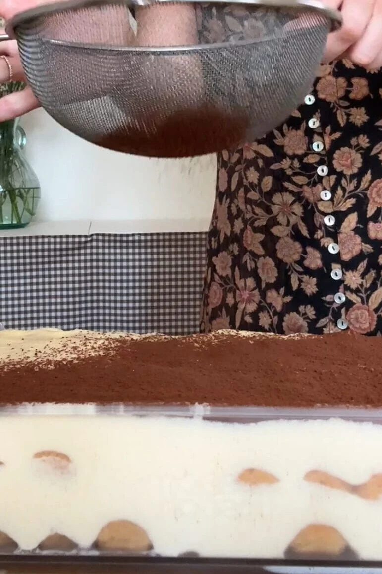 powdering cocoa powder on baileys tiramisu.