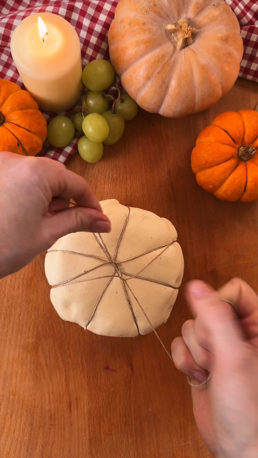 Tying string around the pastry to shape the pumpkin.