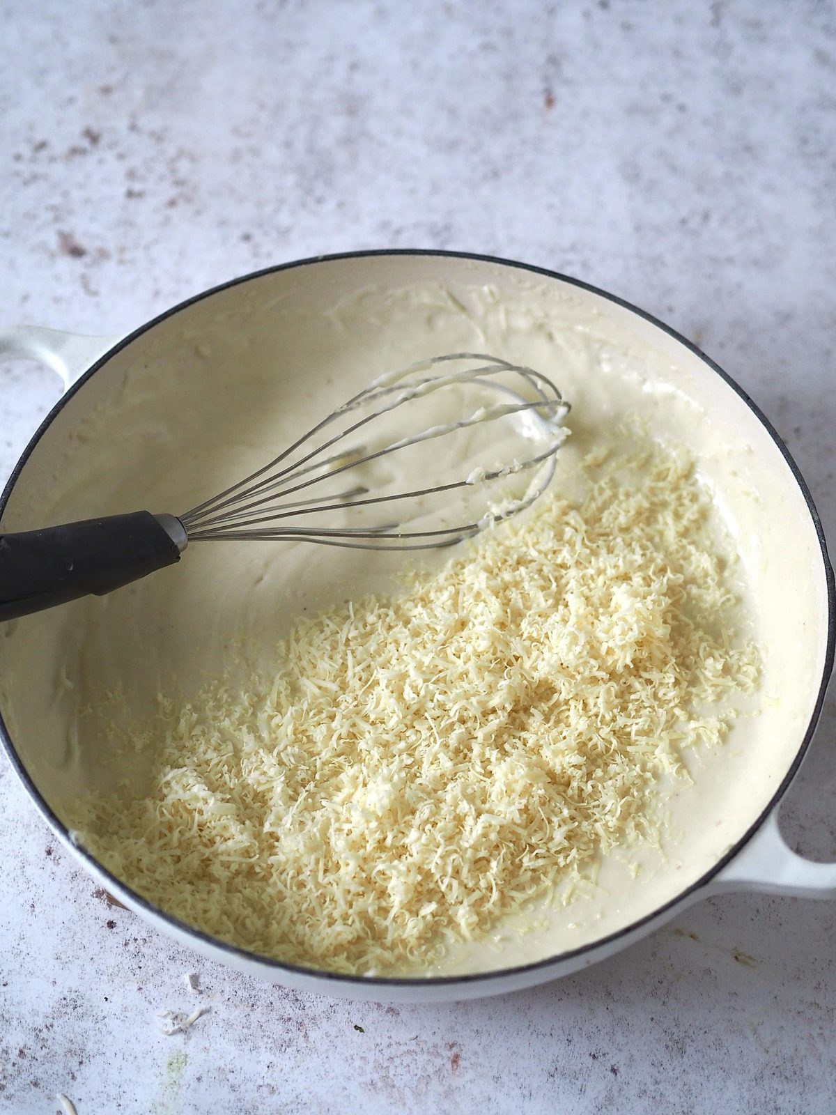 Adding cheese to white sauce.