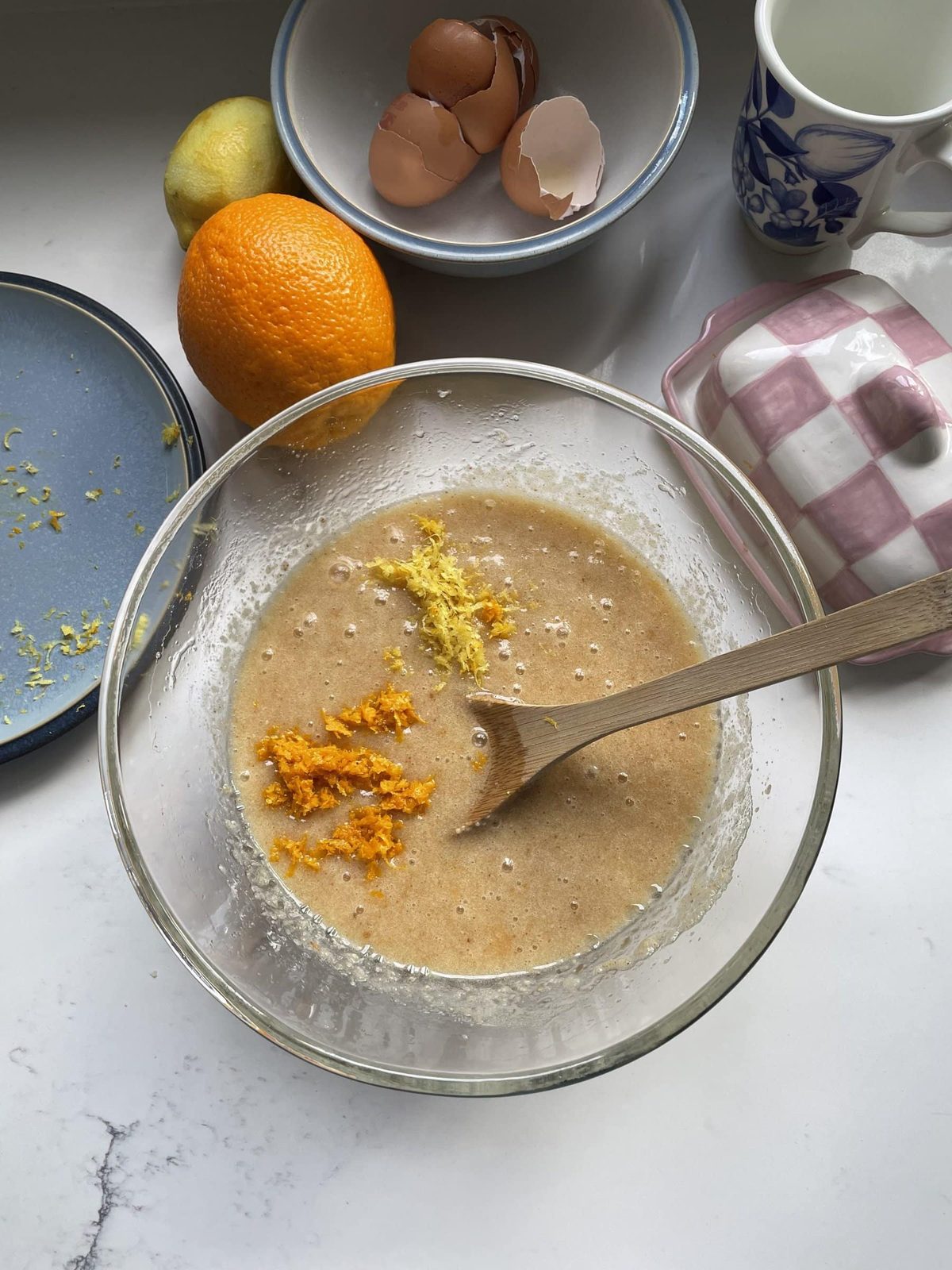 Adding orange and lemon zest to the cake mix in the glass mixing bowl.