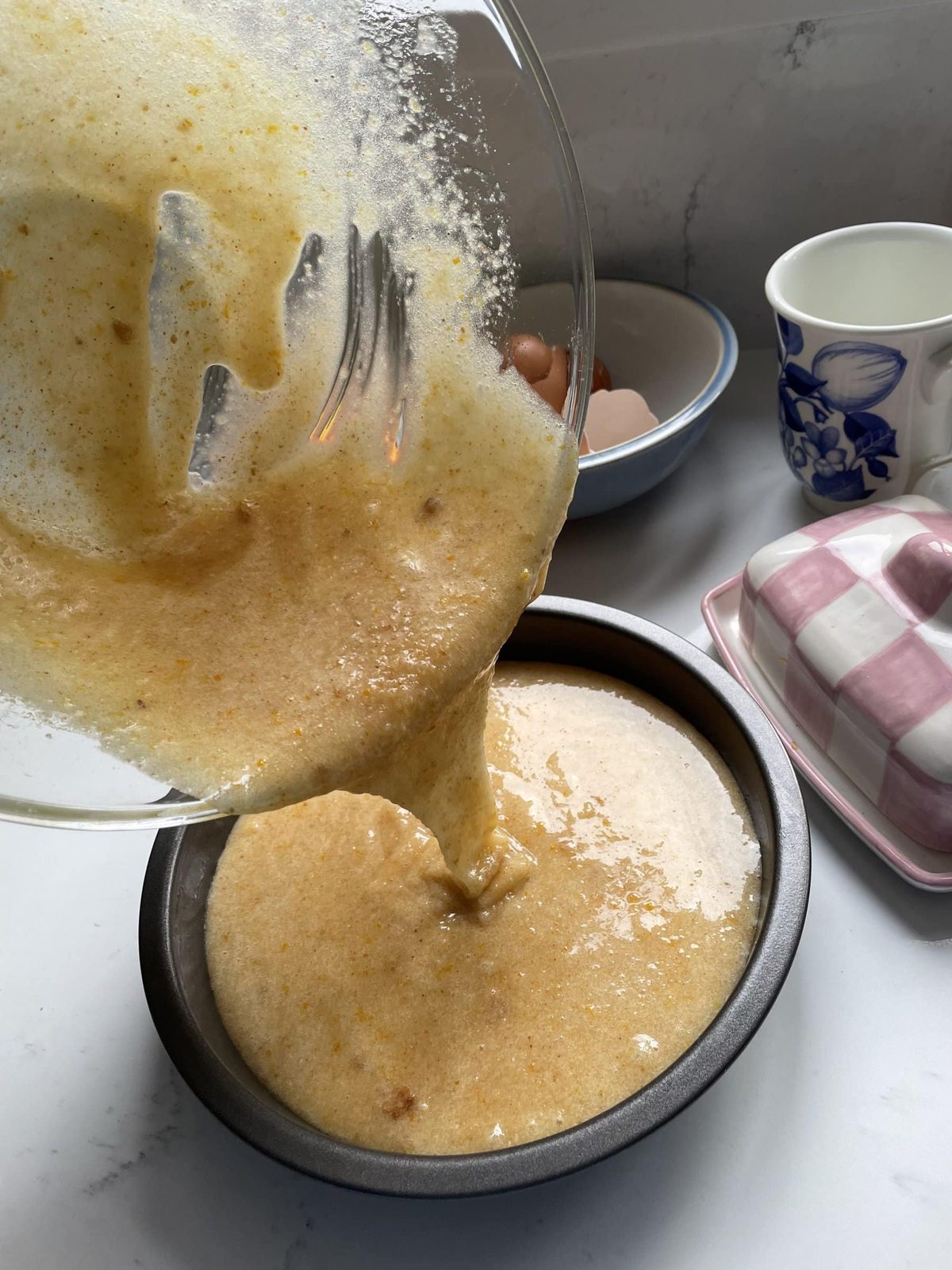 Pouring Tunisian orange cake mix into lined cake tin.