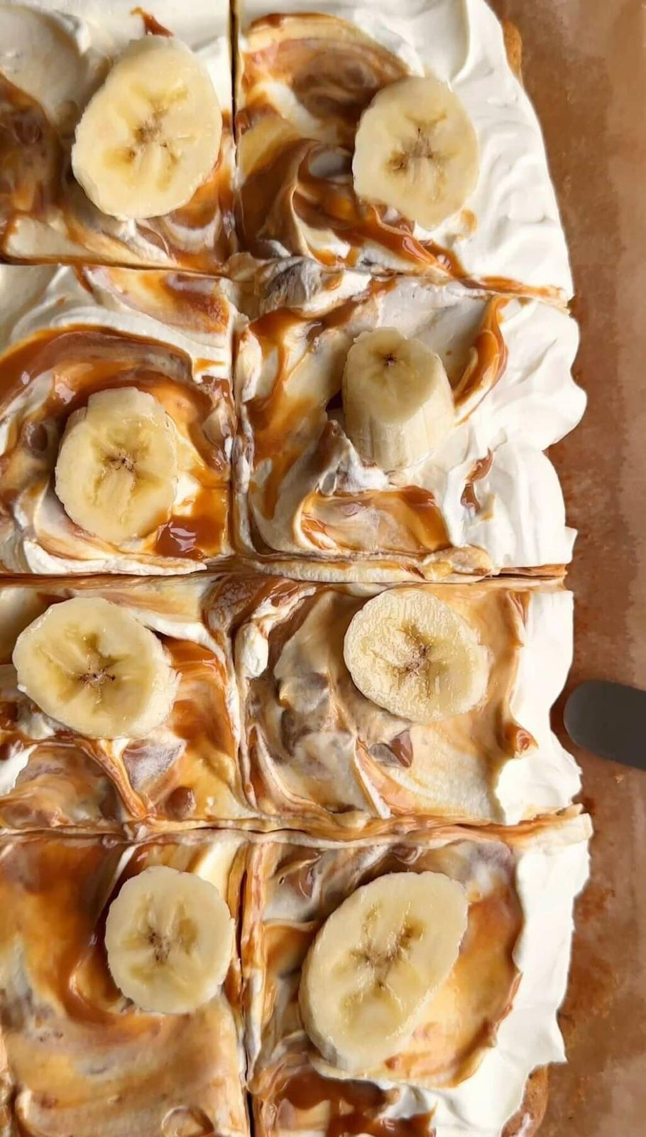 sliced squares of banana bread bars with swirled caramel icing on top and banana slices