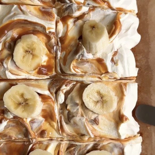 sliced squares of banana bread bars with swirled caramel icing on top and banana slices