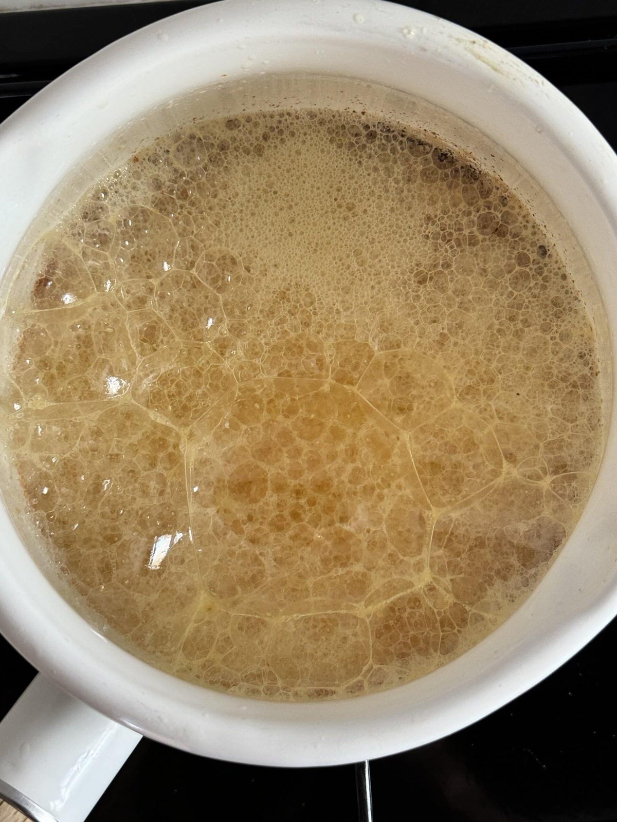 Butter browning in small white pan on the stove.