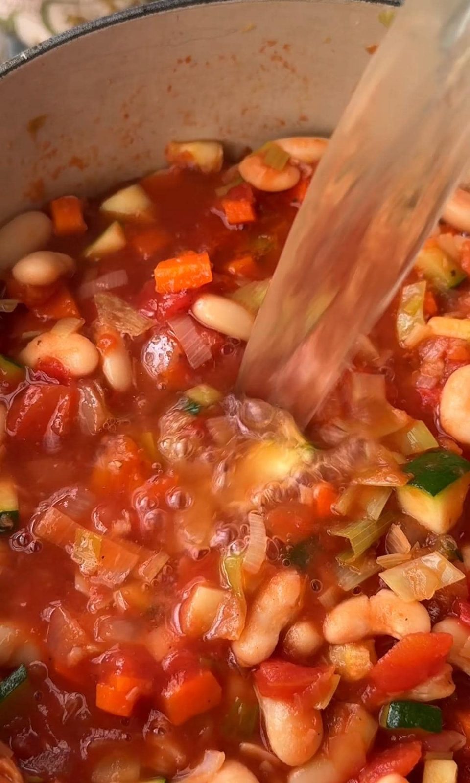 adding stock to bean stew.