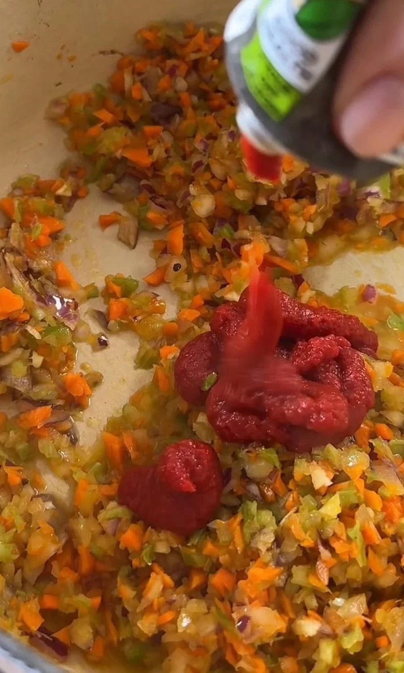 Stirring tomato paste and red wine into the soffritto.