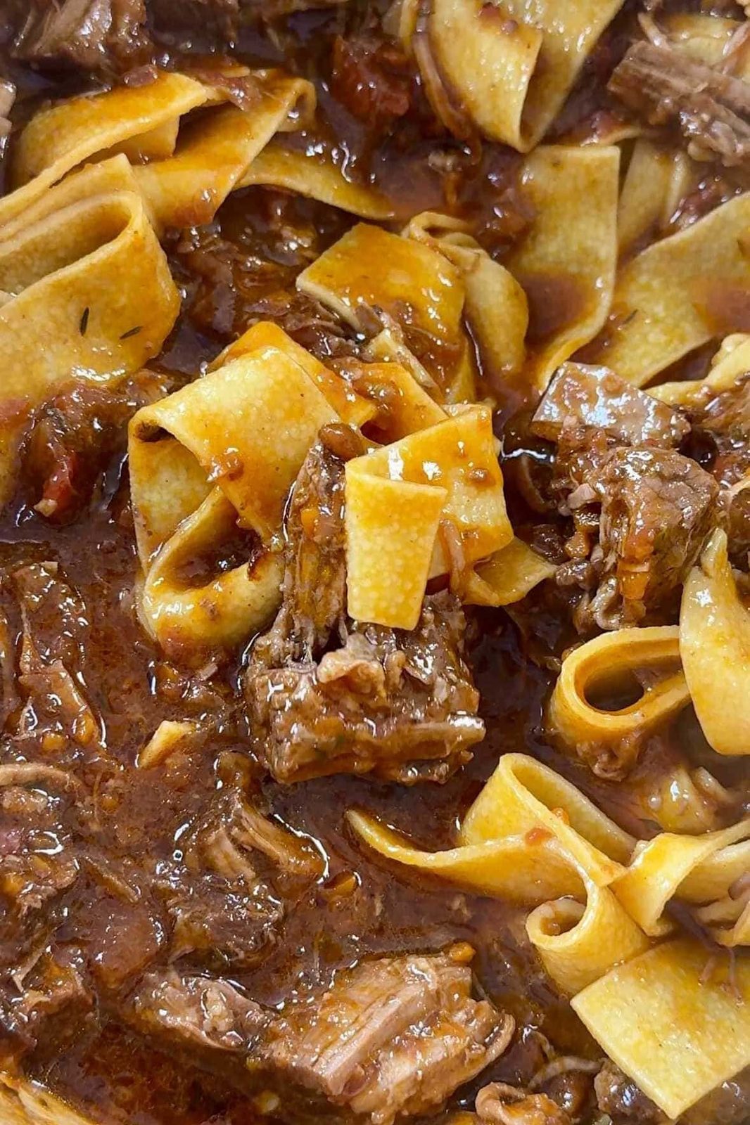 Glossy beef short ribs ragu in a bowl with Parmesan.