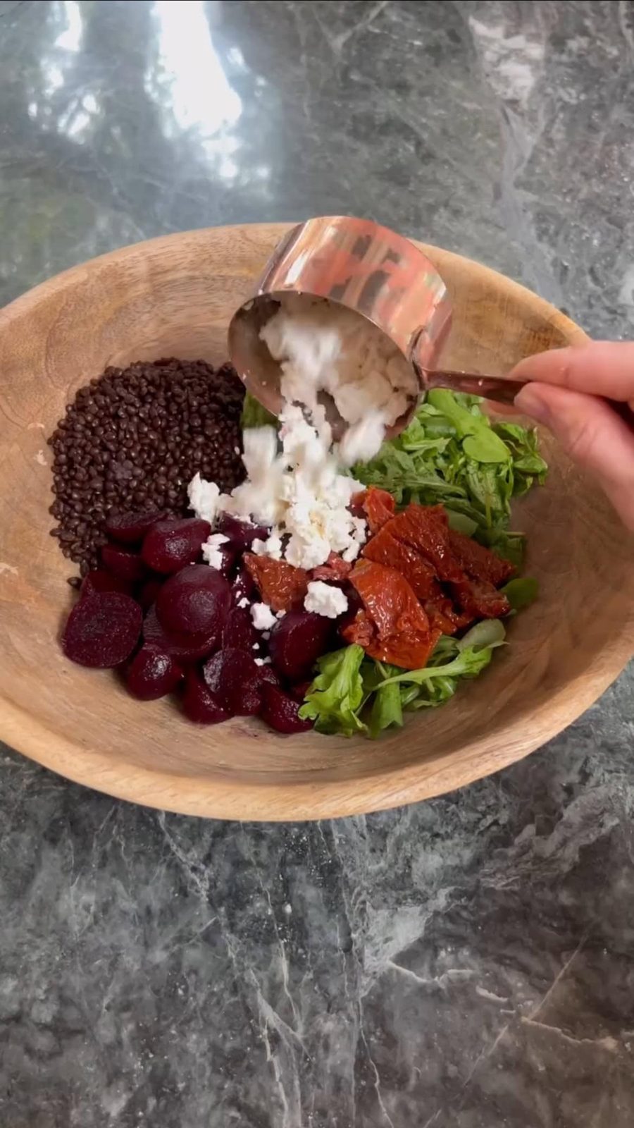 Adding feta cheese to bowl with chopped beetroot and other salad ingredients.