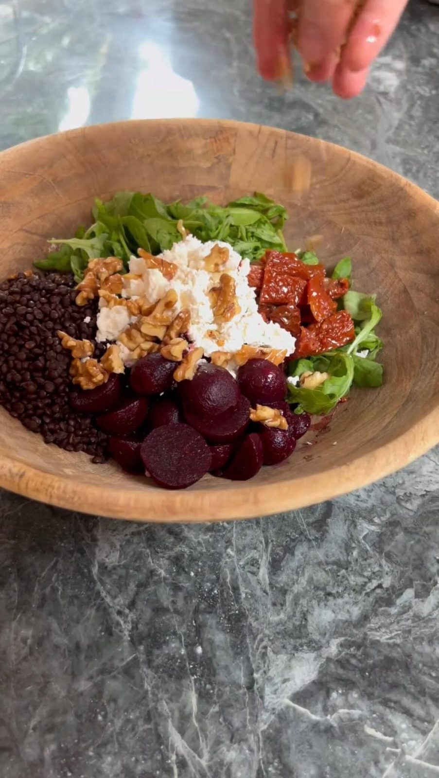Adding crushed walnuts to salad bowl.
