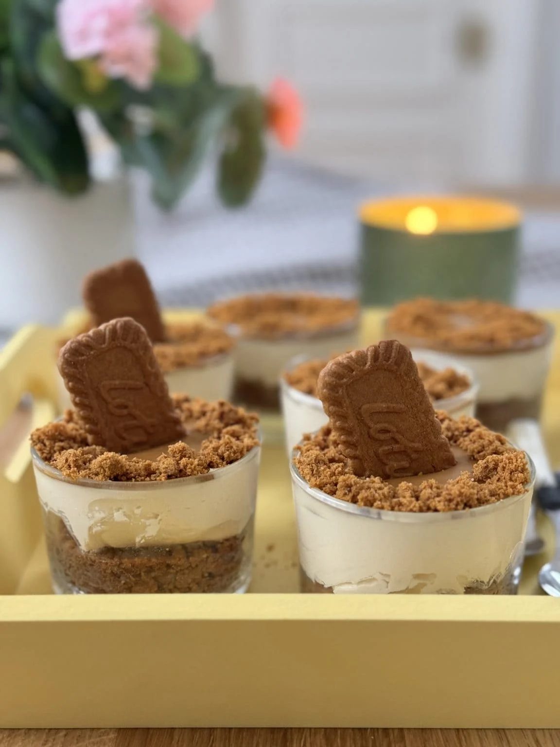 No bake Biscoff cheesecakes with Biscoff biscuits in the middle on a yellow tray.
