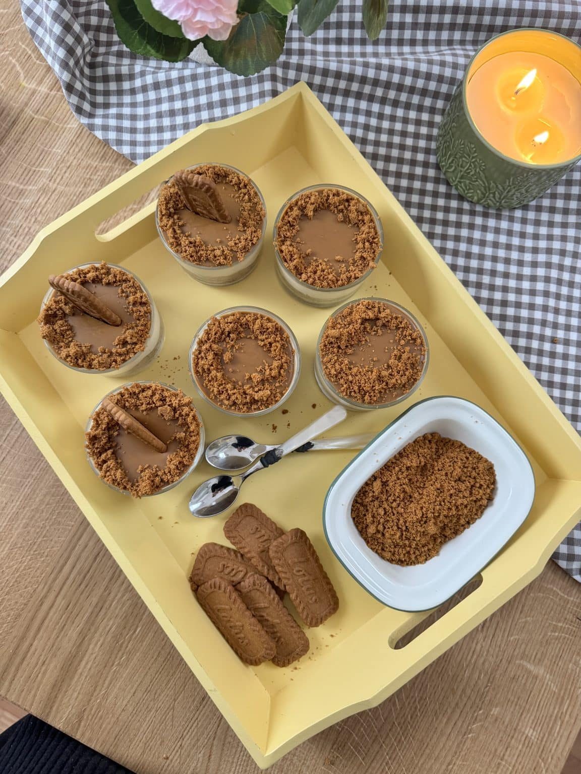 Ramekins filled with Biscoff cheesecakes on a wooden tray with extra Biscoff biscuits