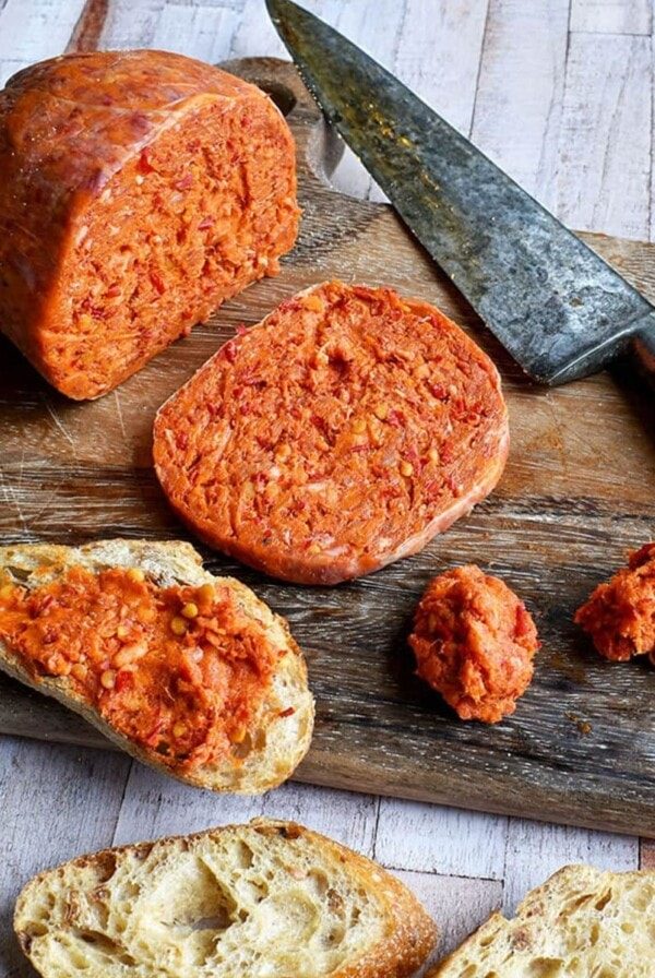 sliced nduja on wooden board and spread onto bread.
