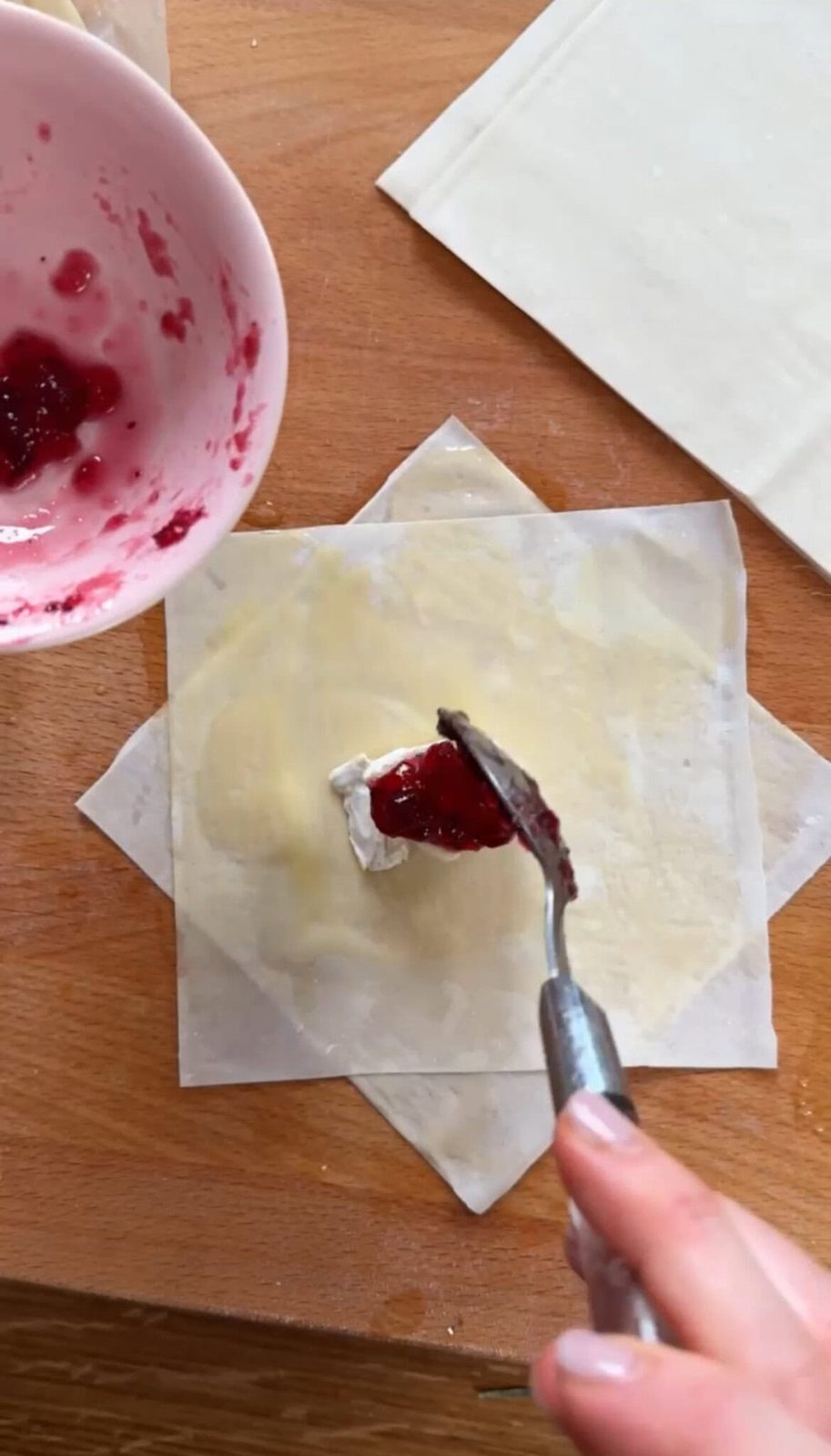 Adding cranberry sauce to buttered filo dough sheets.