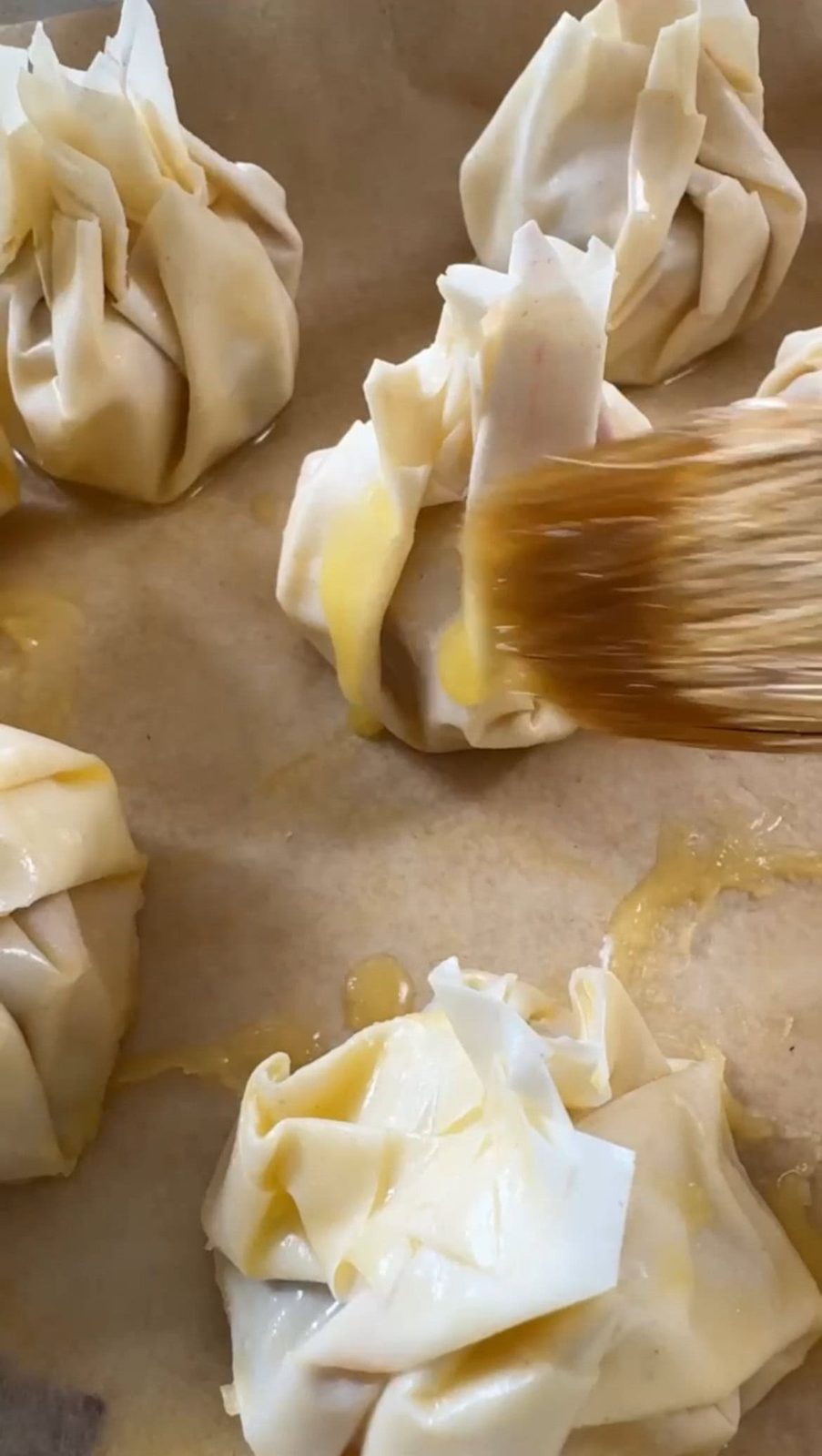 Brushing filo pastry parcels with melted butter.