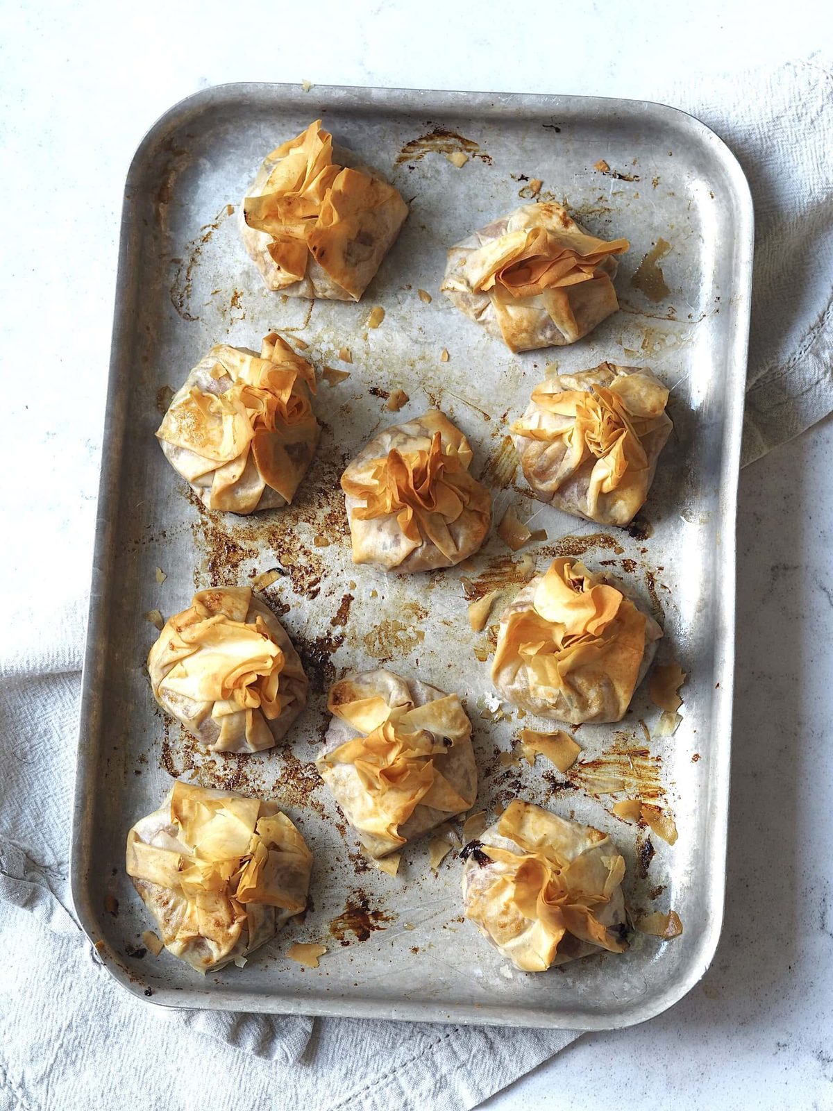 Baked cranberry sauce and brie filo parcels on a metal baking sheet.