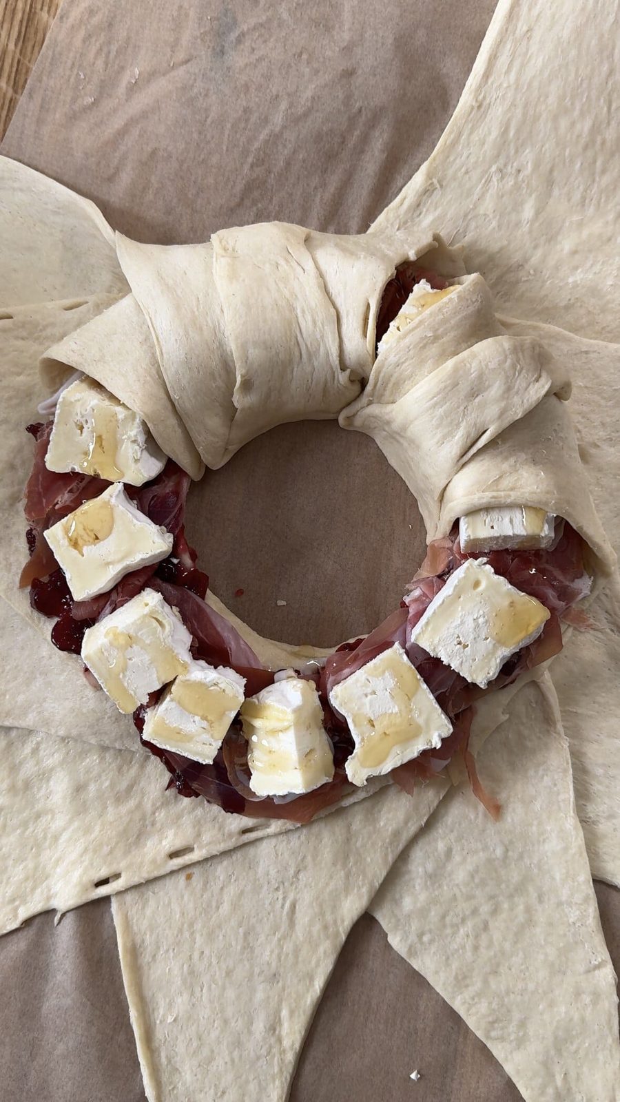 Partially wrapped crescent roll wreath with filling.