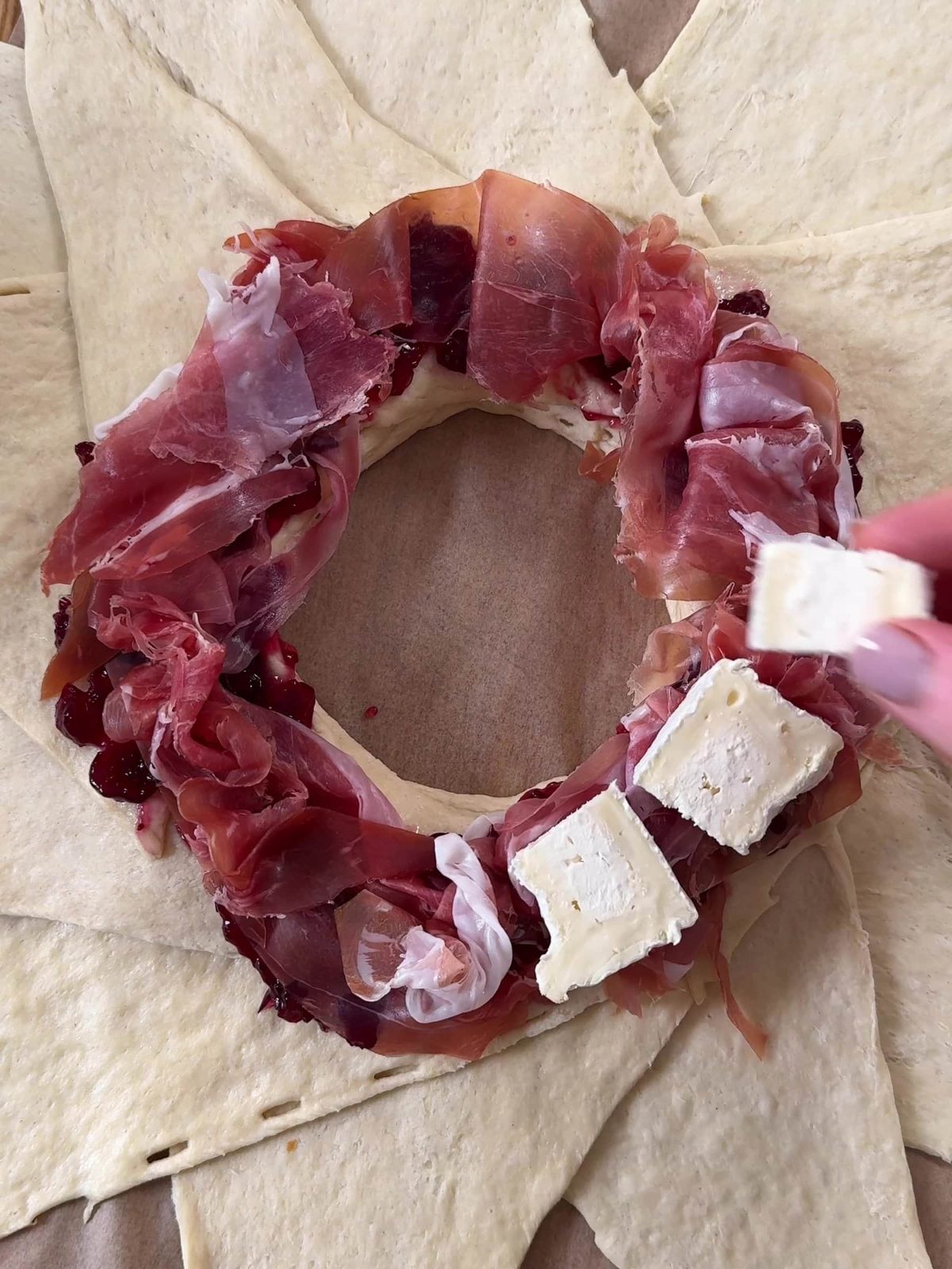 Adding Parma ham and brie on top of the dough.
