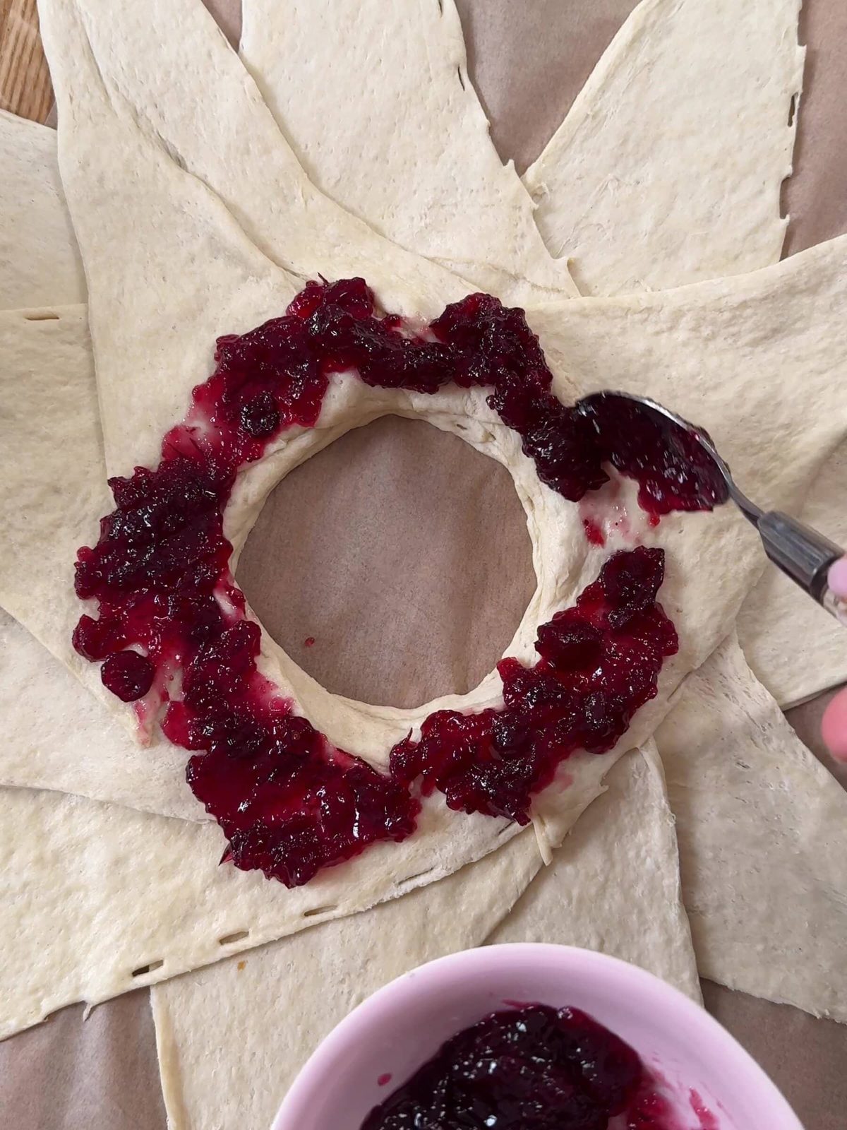 Adding cranberry sauce around the croissant dough.