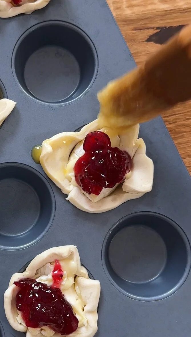 Burshing egg over puff pastry with Brie and cranberry sauce.