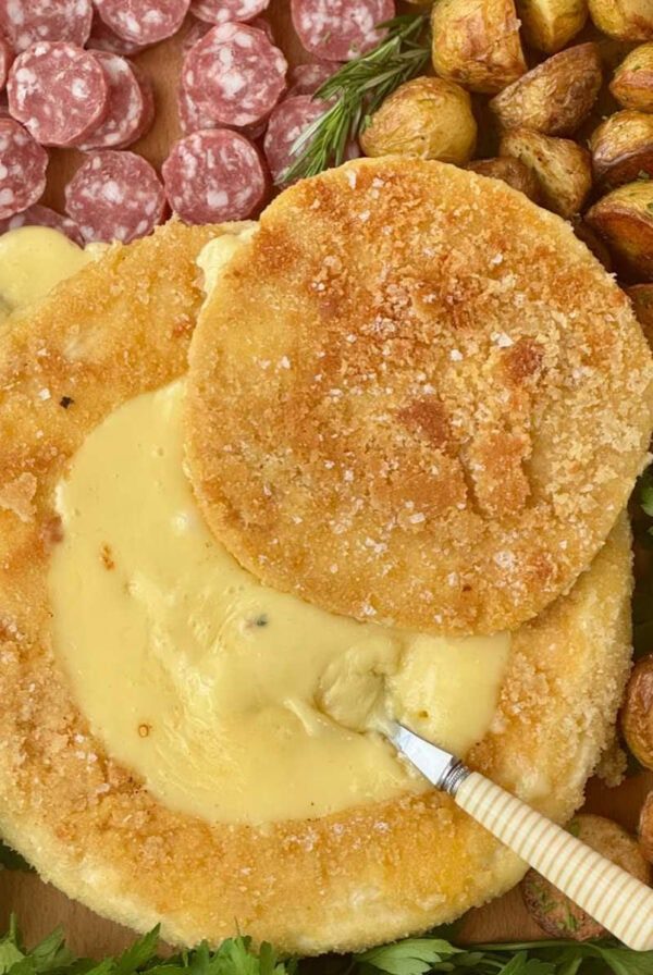 deep fried brie with a spoon on a charcuterie board.