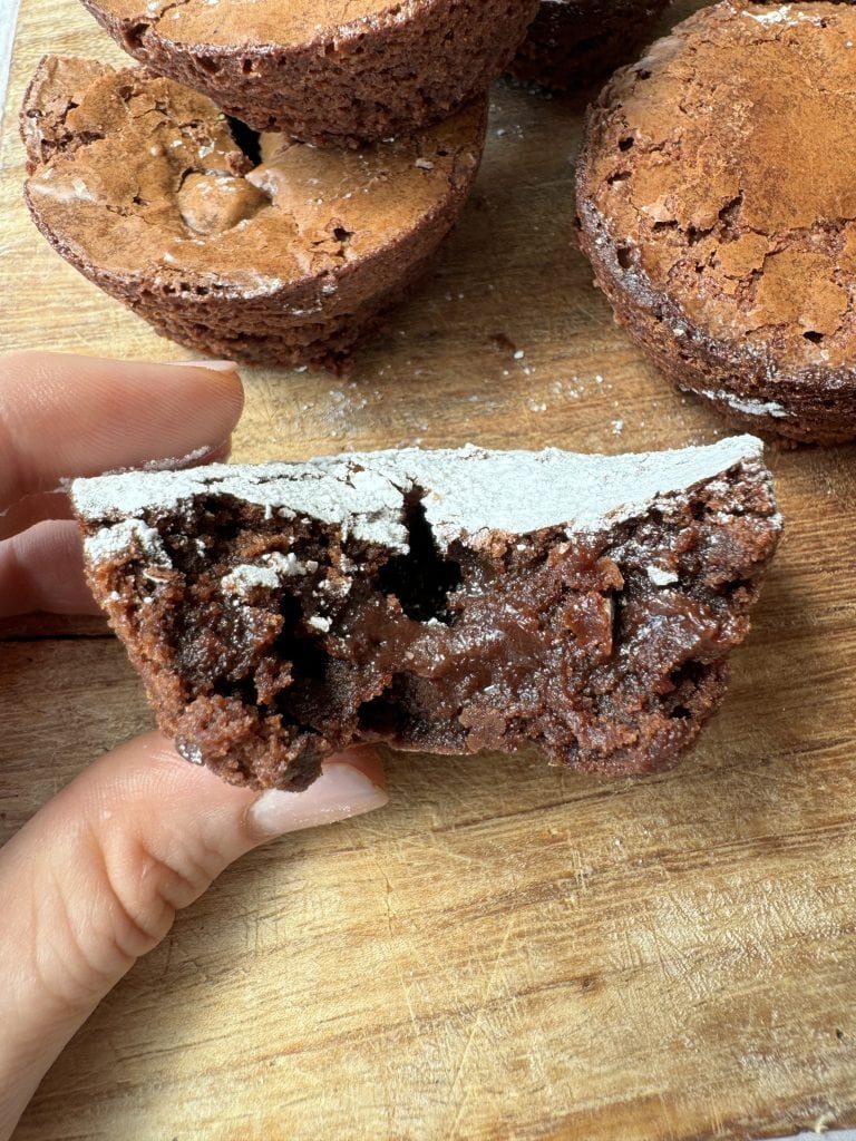 Woman holding half a fudgy brownie bite.