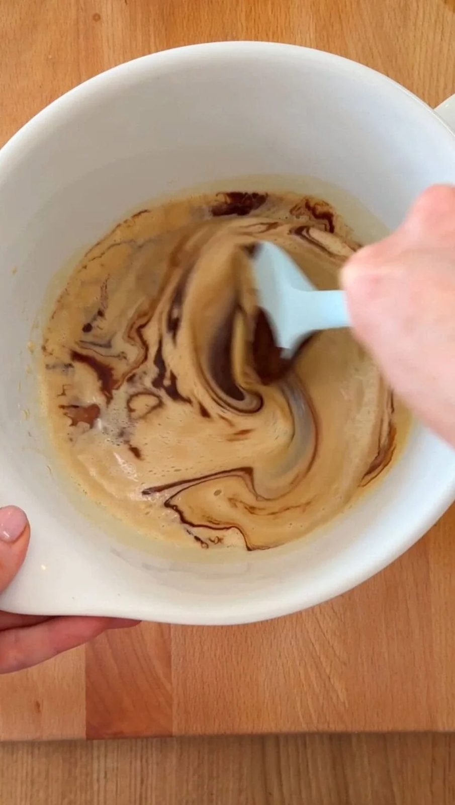 Mixing together beaten eggs and chocolate.