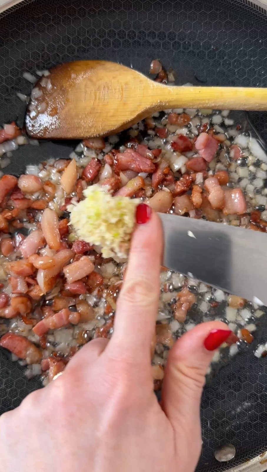 Adding garlic to frying pancetta.