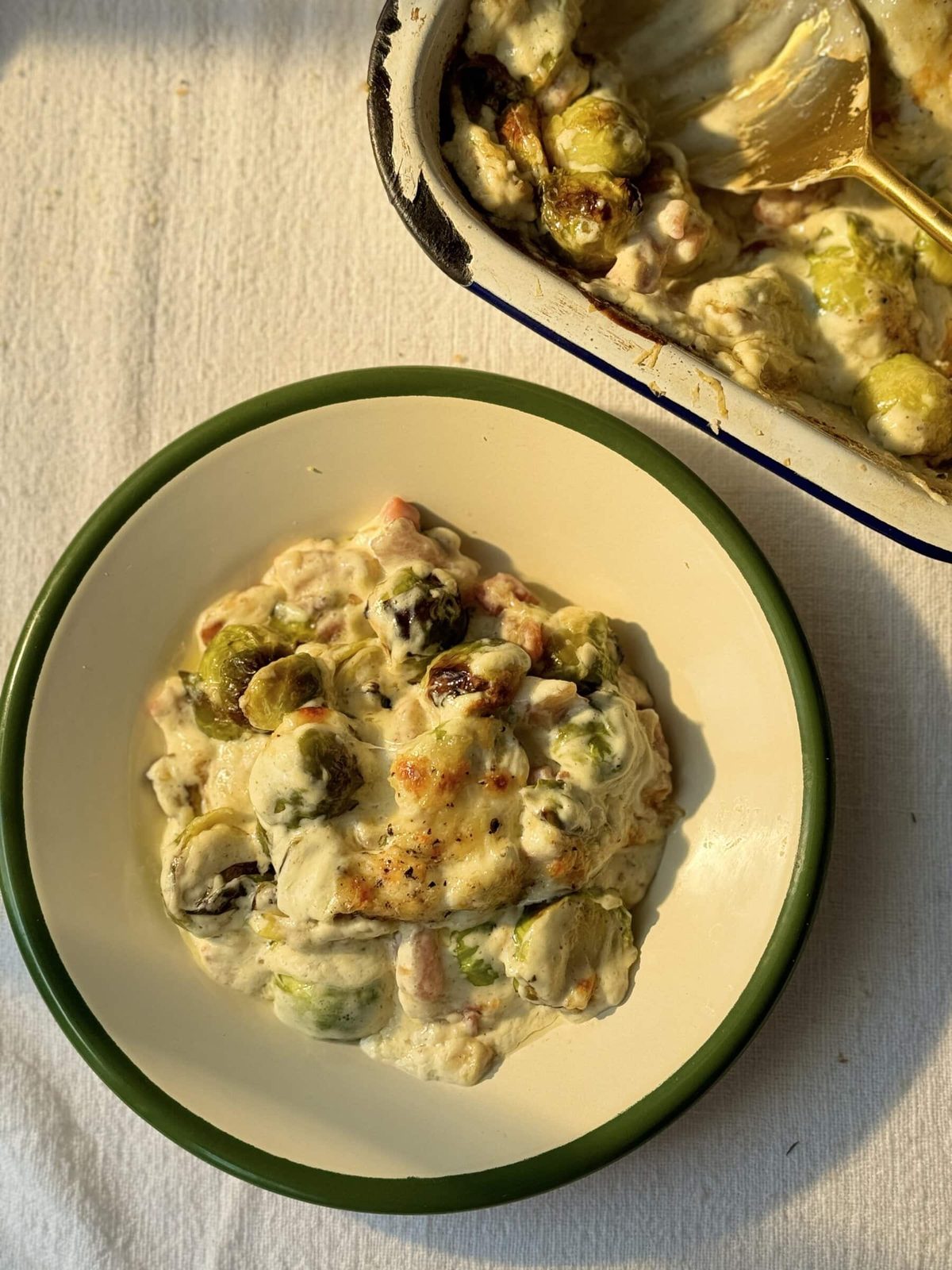 Serving of Brussels sprouts and bacon casserole on a white plate with green rim.