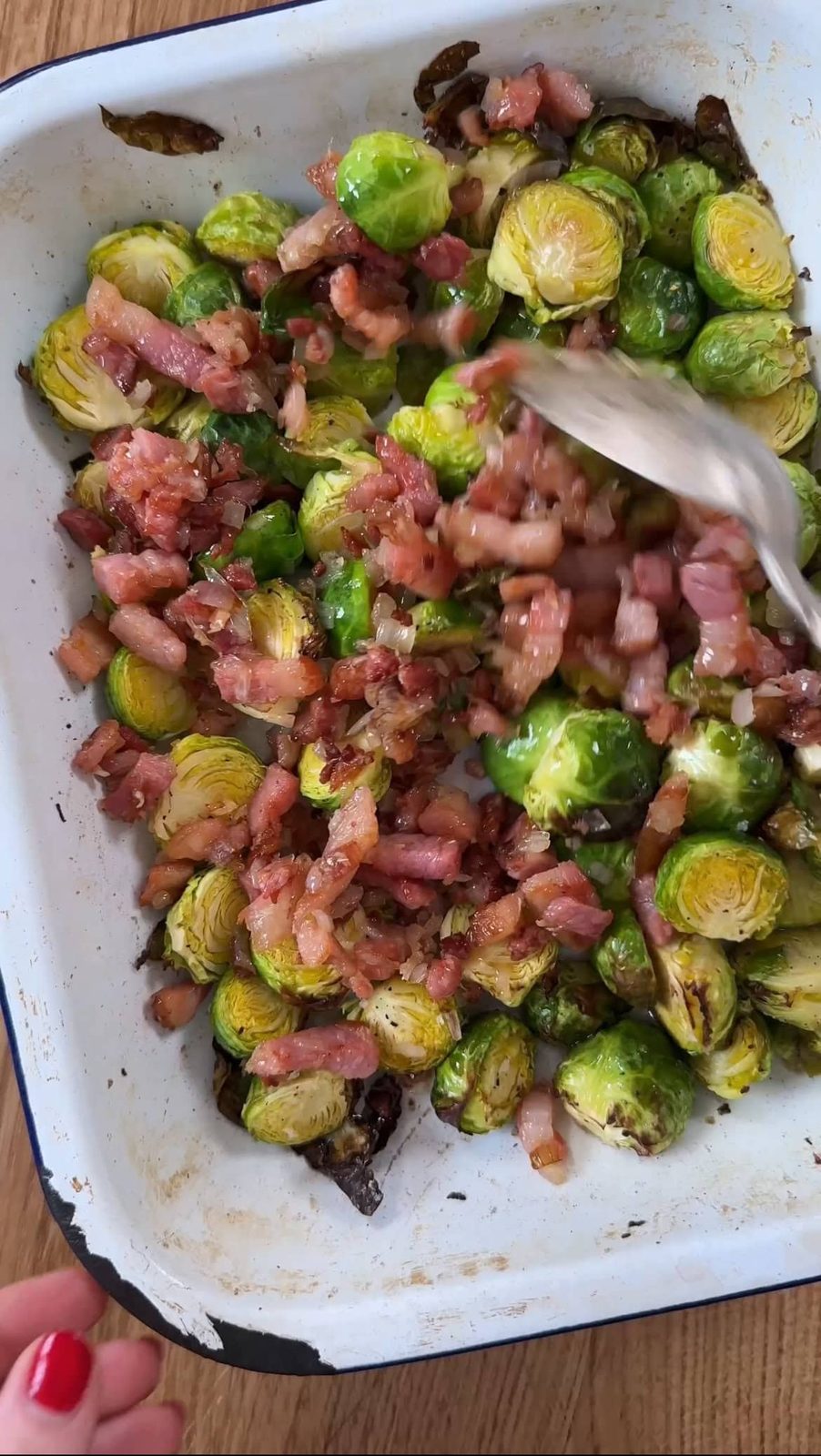Adding fried pancetta to the Brussels sprouts.