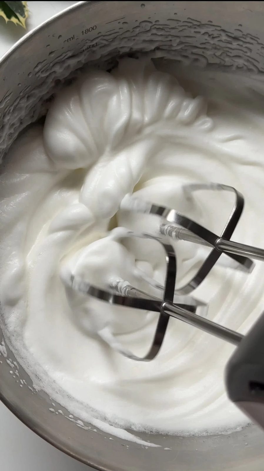 adding sugar and whipping egg whites to stiff peaks.
