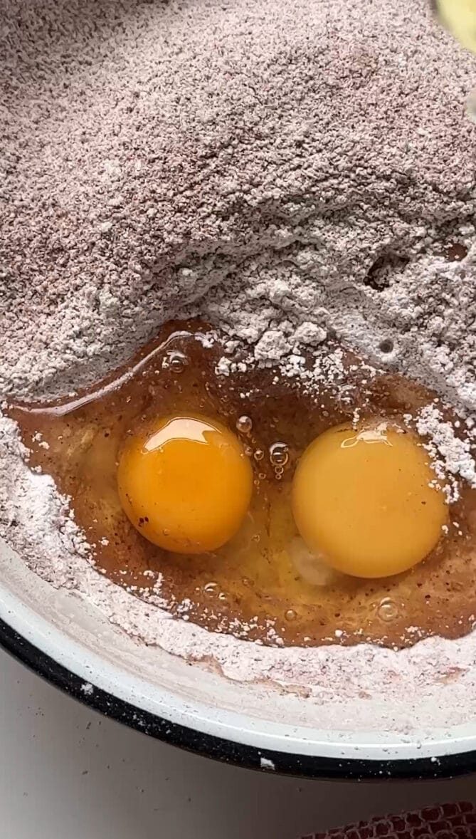 Adding eggs to flour.