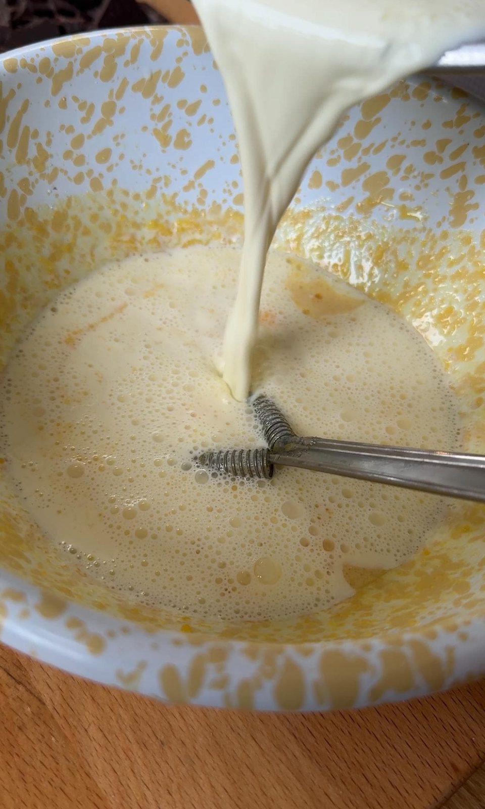pouring hot cream into egg yolks to temper.
