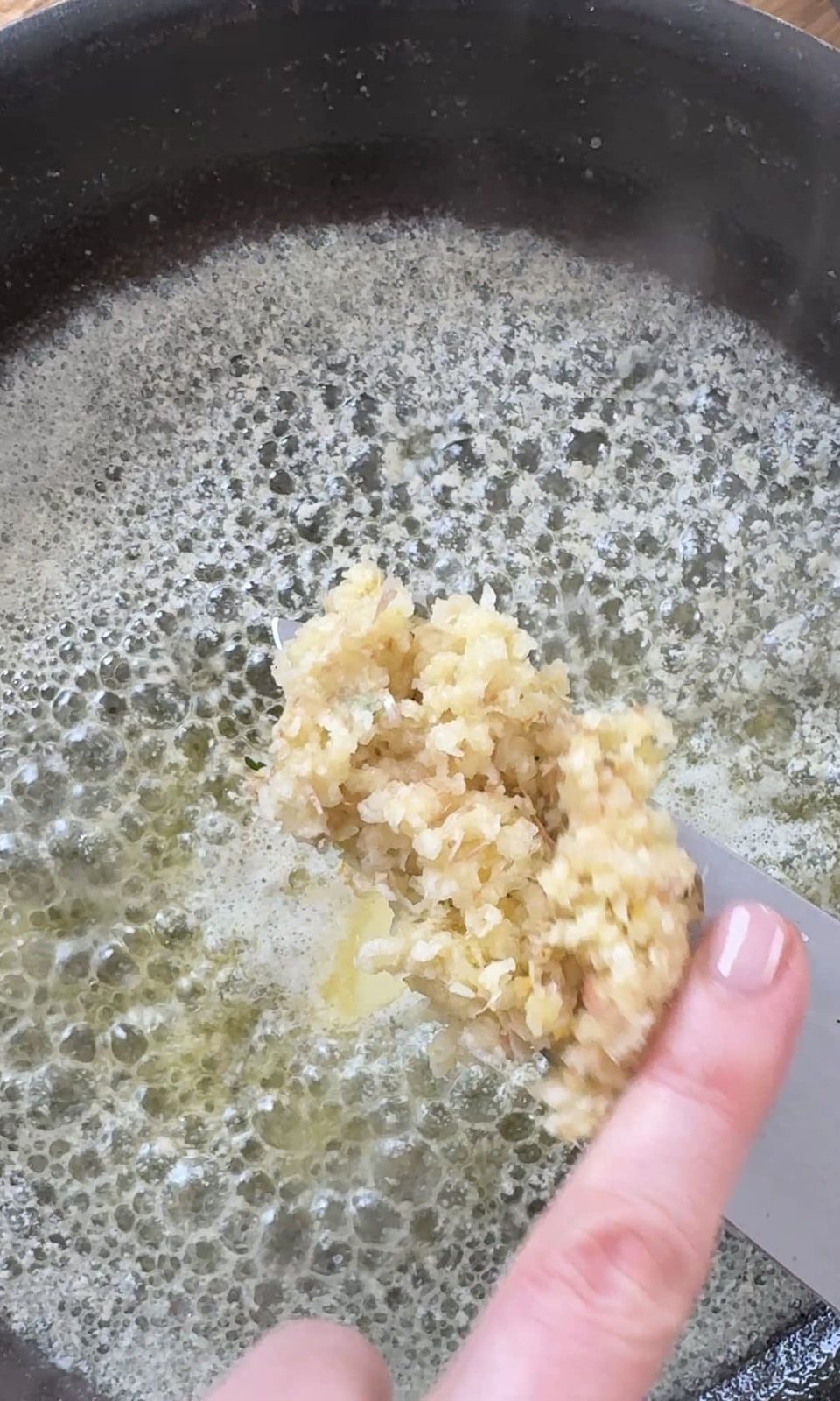 Adding garlic to the butter in the pan.