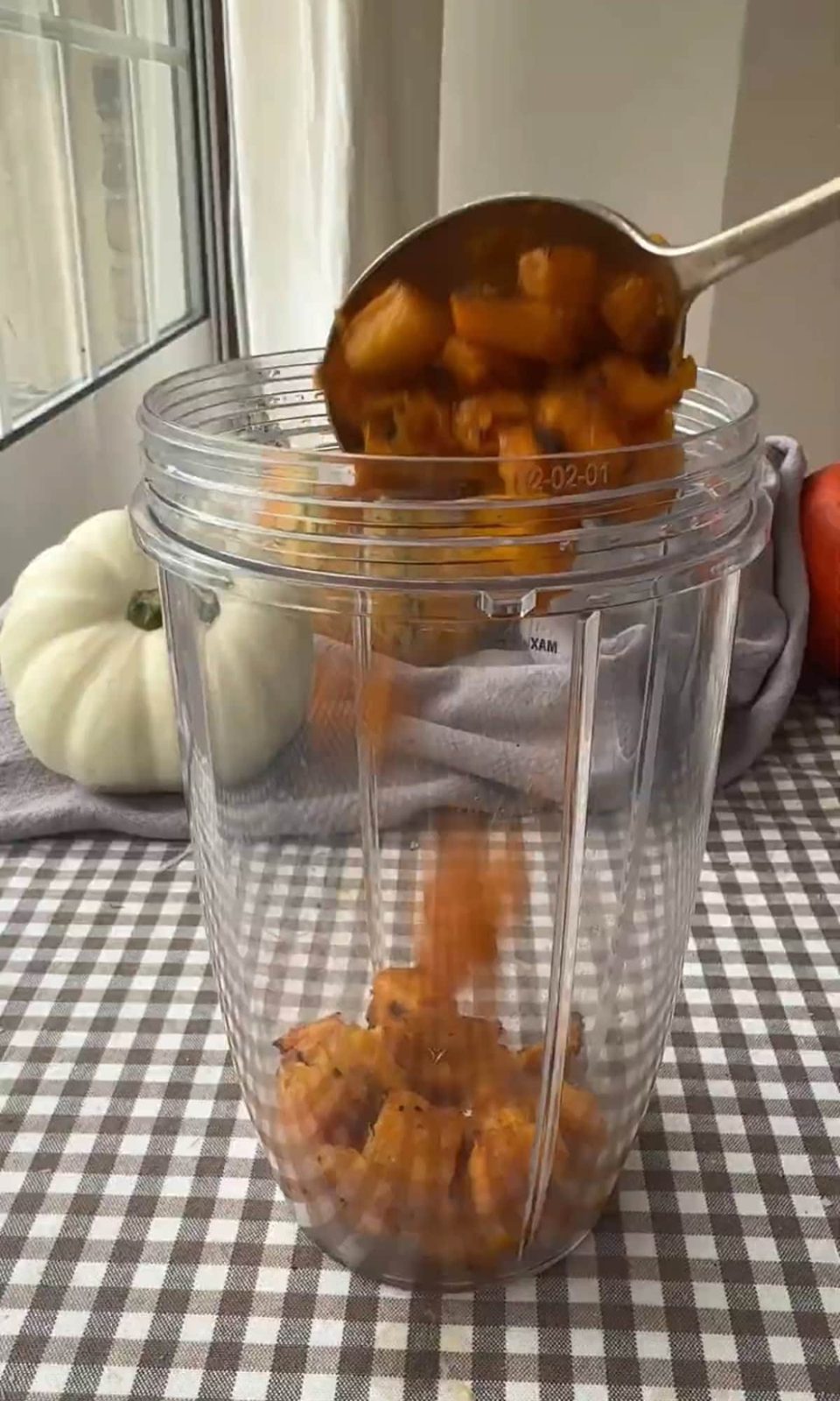 Spooping diced roasted pumpkin into food processor.