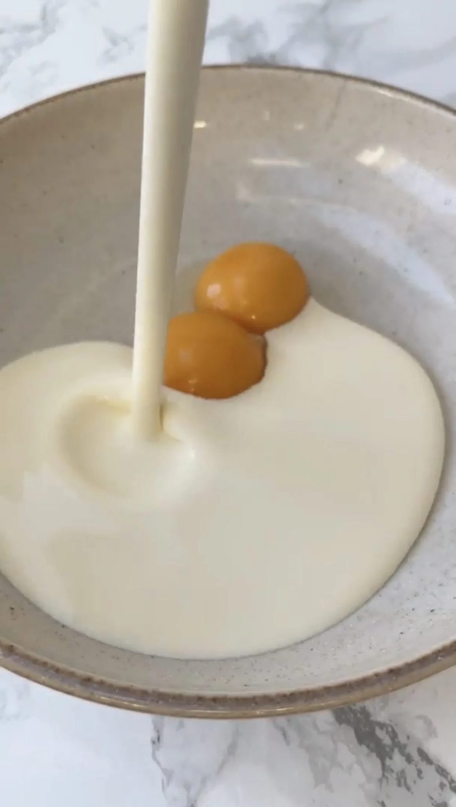 double cream poured into a bowl with 2 egg yolks