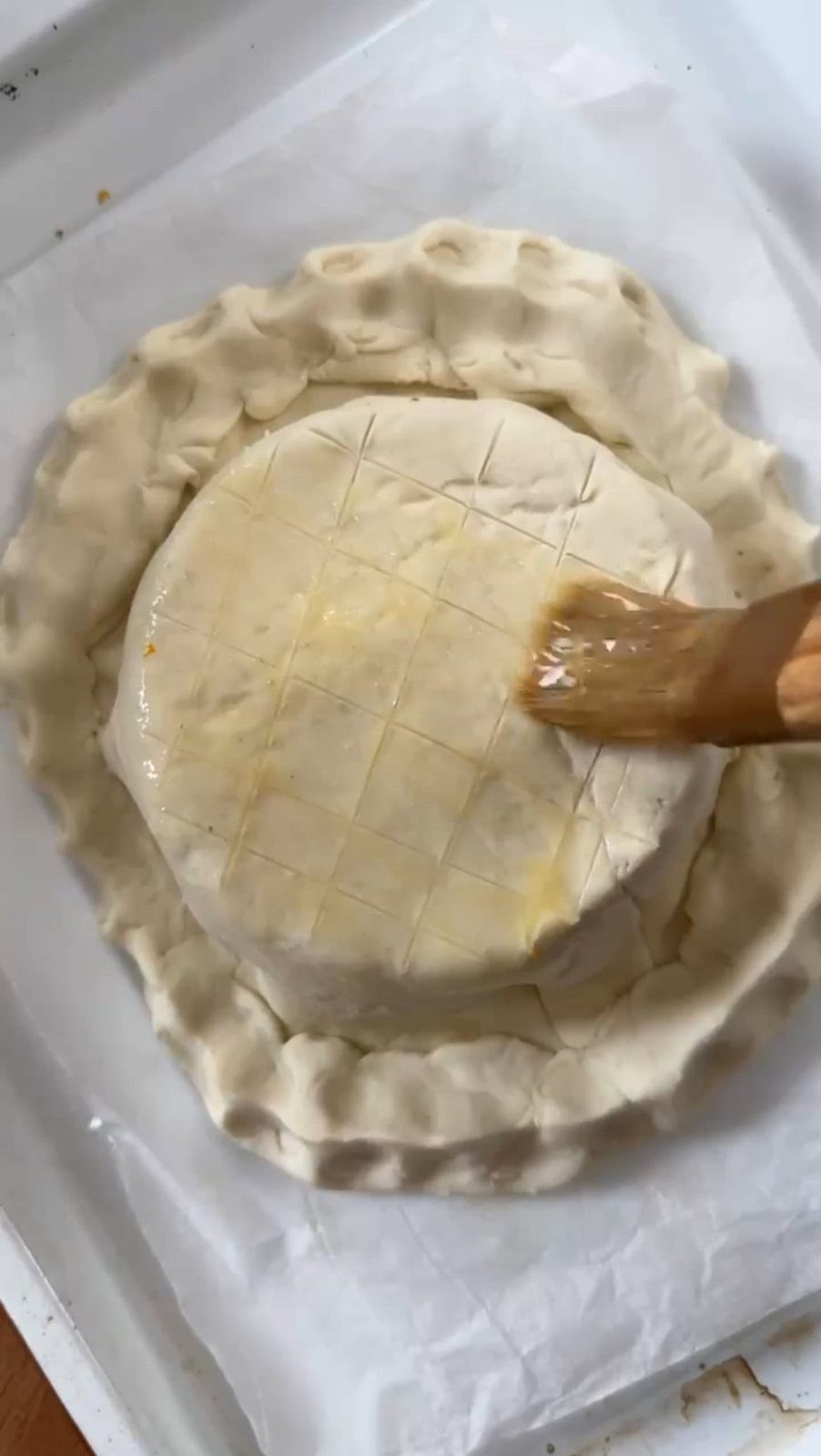 Brushing egg wash over round pastry for en croute.
