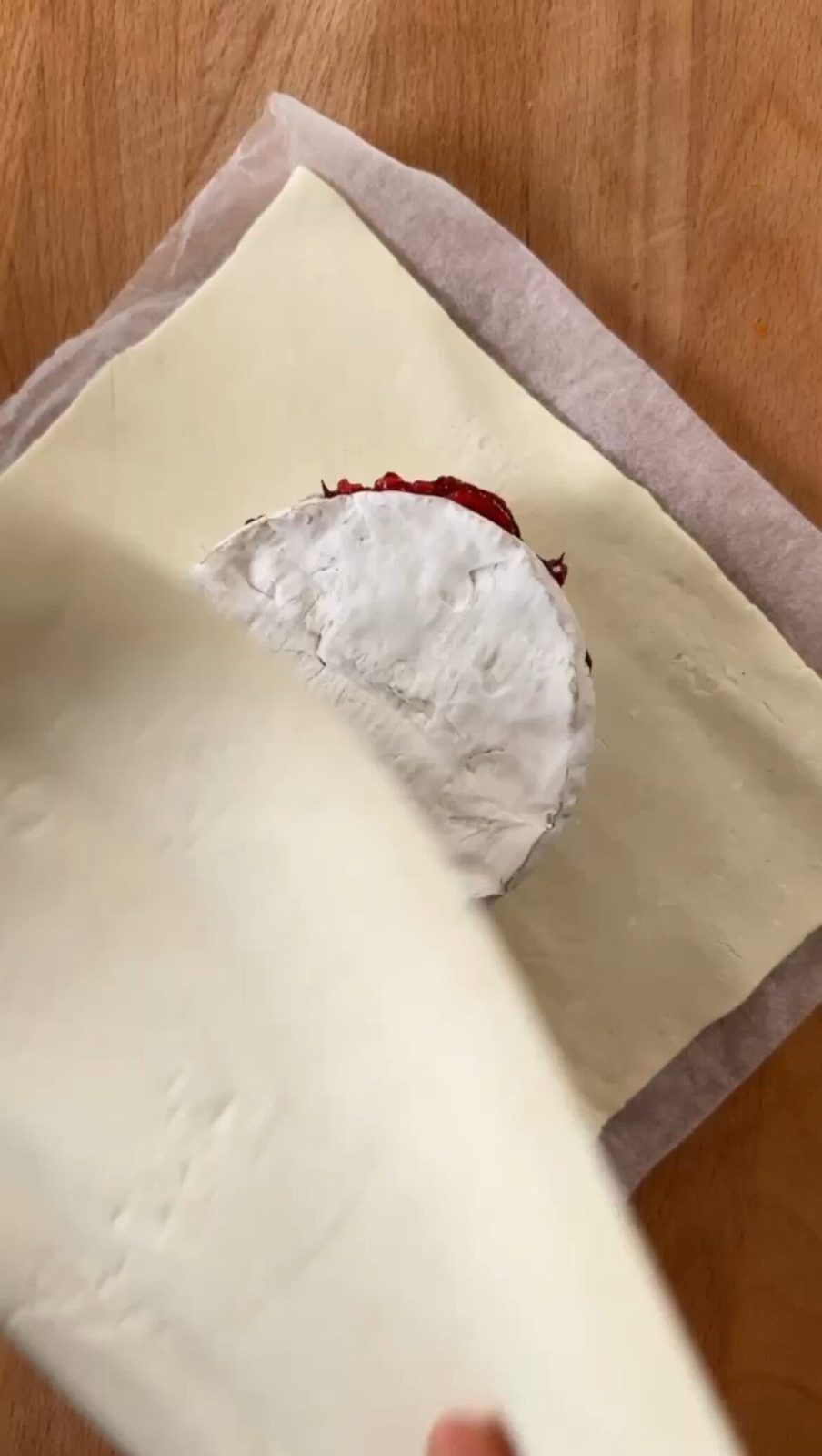 Adding top layer of pastry dough over camembert and cranberry sauce.