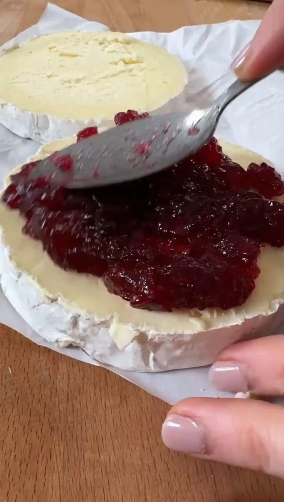 Topping Camembert wheel with cranberry sauce.