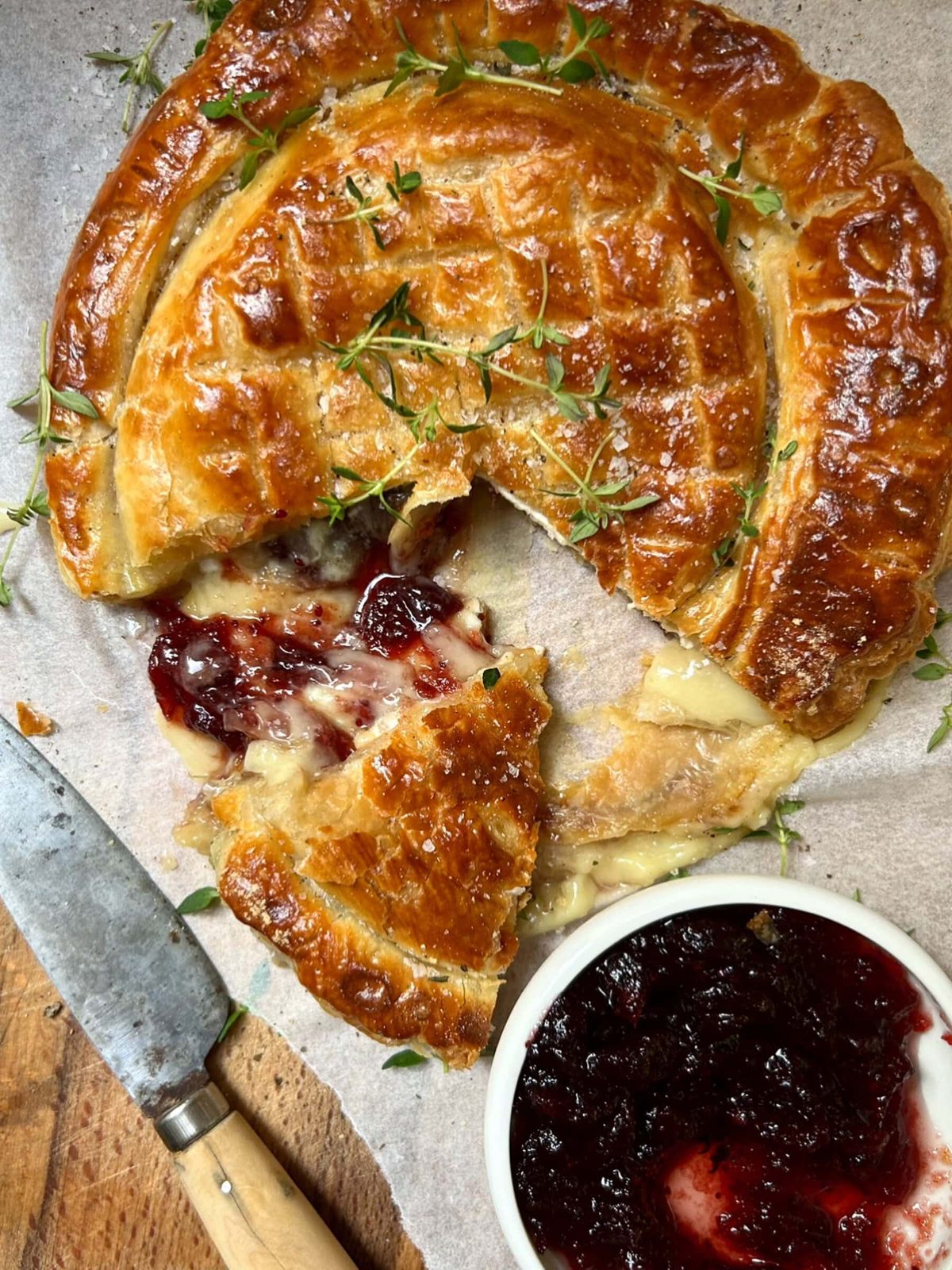 Slicing baked pastry filled with camembert and cranberry sauce.