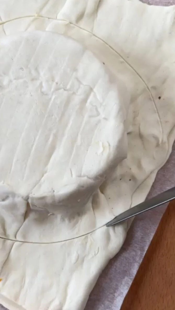 Cutting a circle around pastry dough with knife.