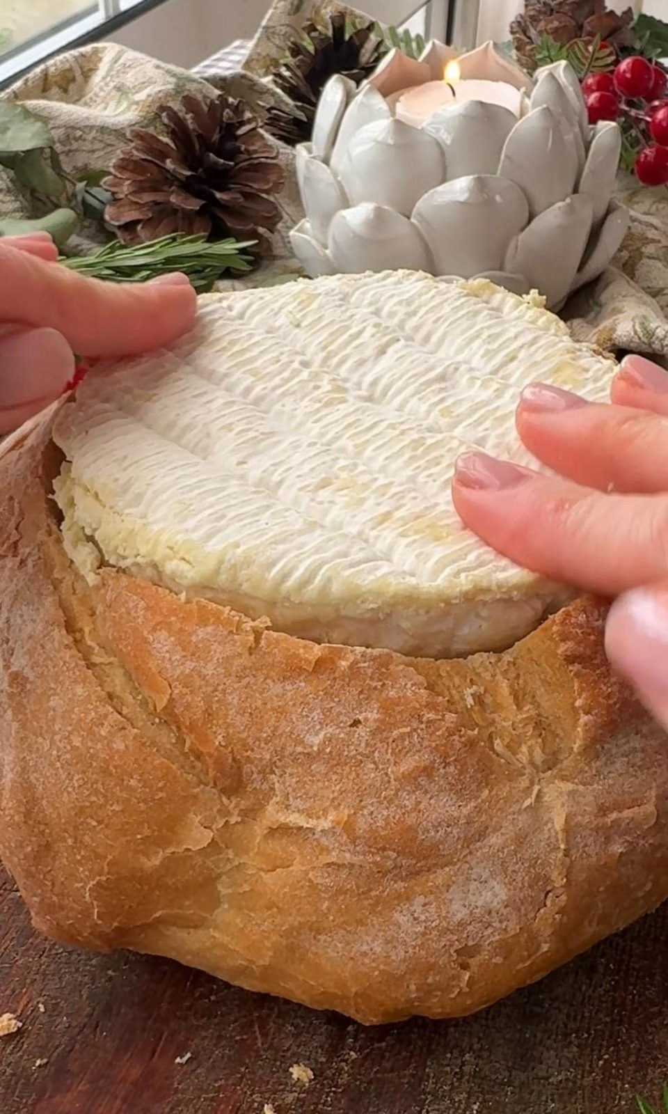 Placing cheese round inside hollow bread loaf.