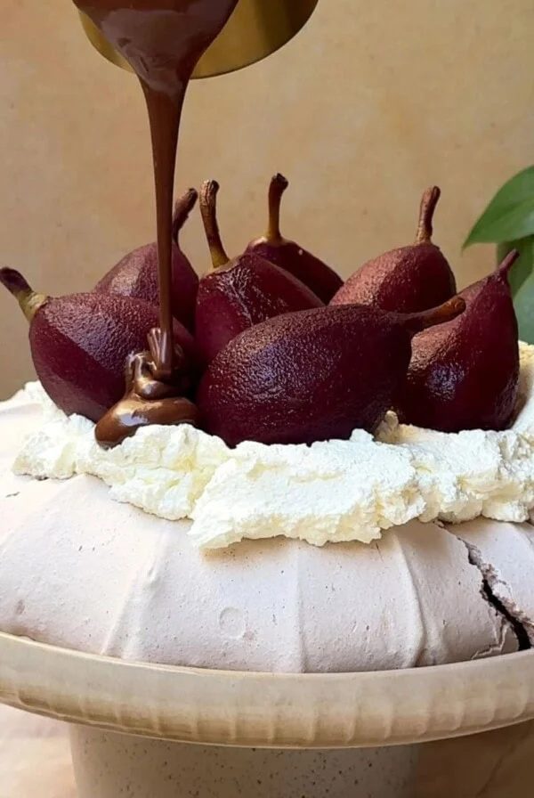 pouring chocolate over christmas pavlova with poached pears.