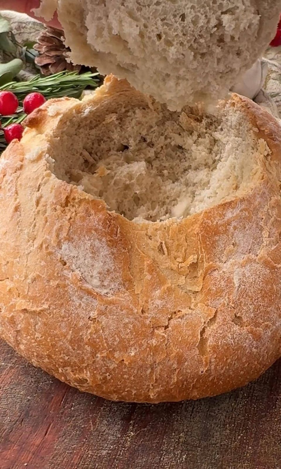 Removing the lid of a round cob bread loaf.